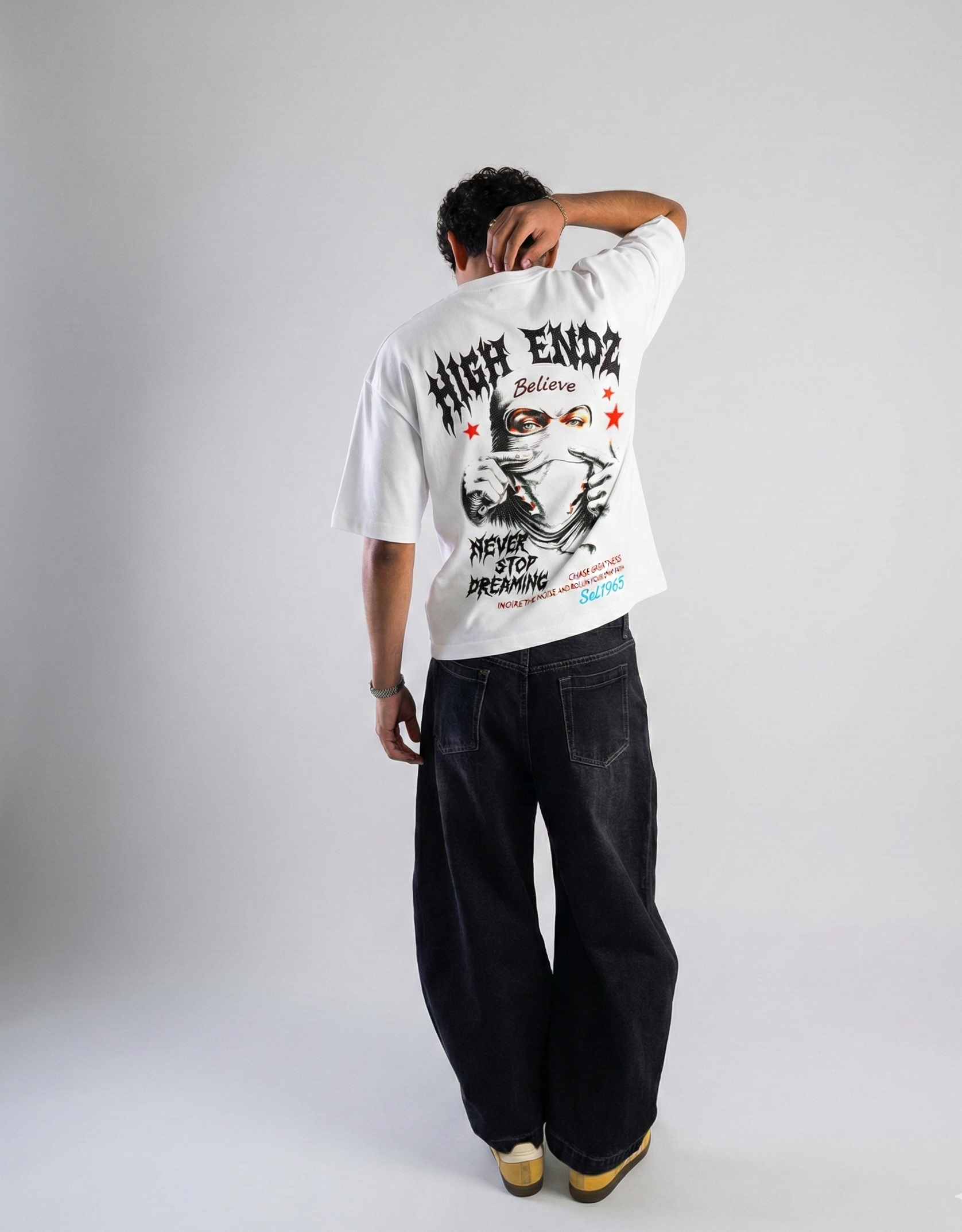 Person wearing a white t-shirt with graphic design and text, standing against a plain background